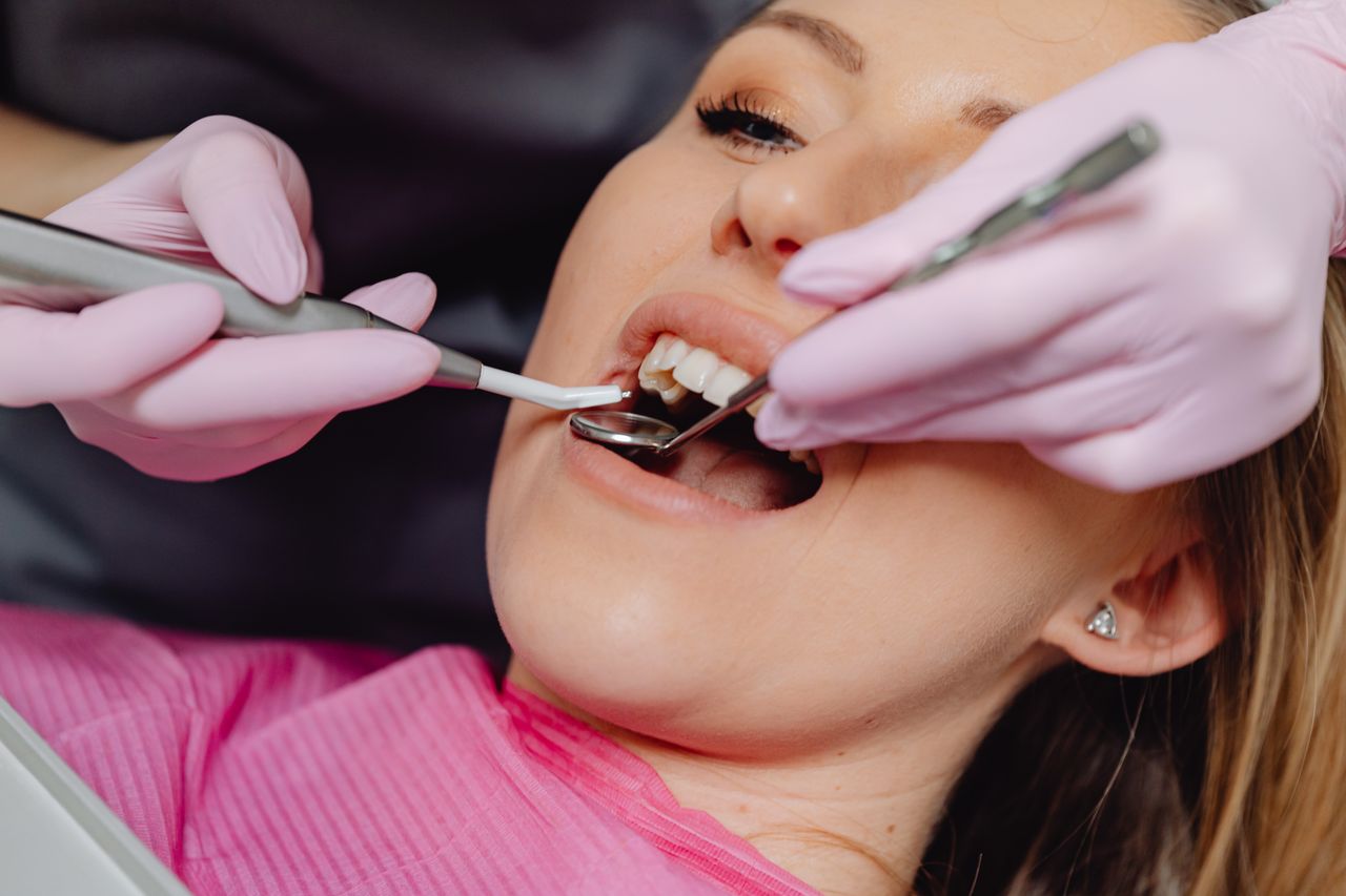 Femeie la consultație stomatologică cu instrumente dentare în gură
